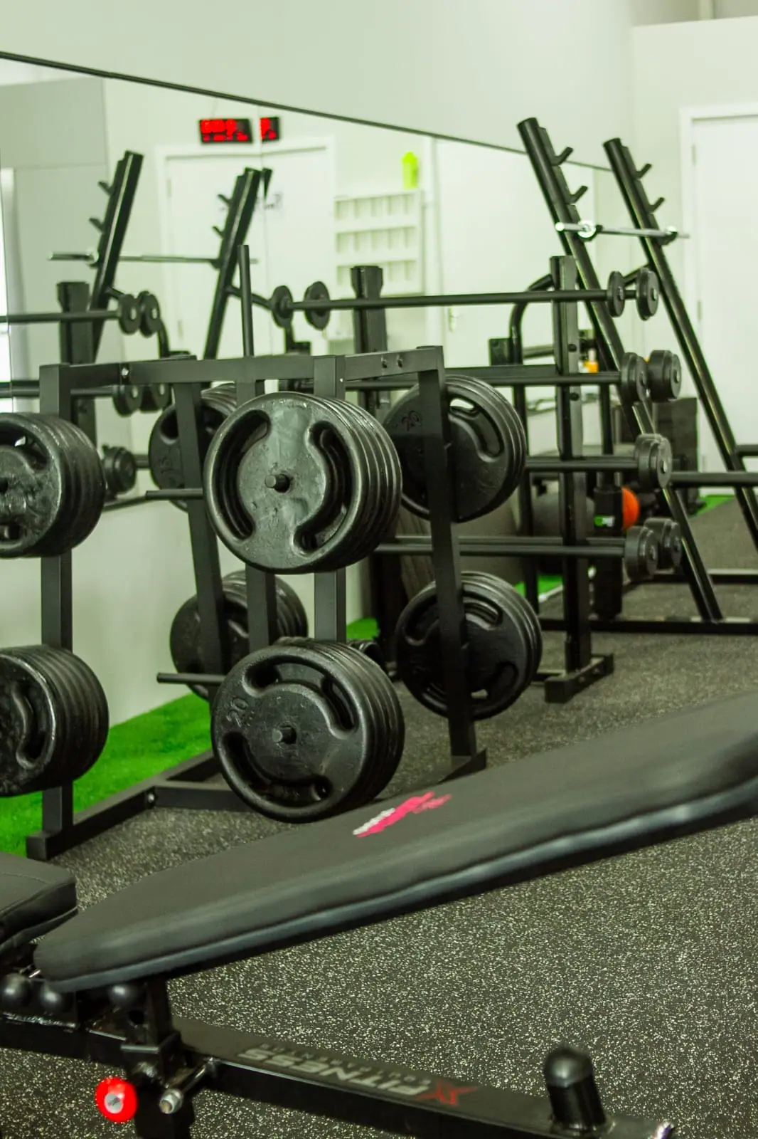 Rack de anilhas e halteres no Zack Studio, com piso de borracha e grama sintética