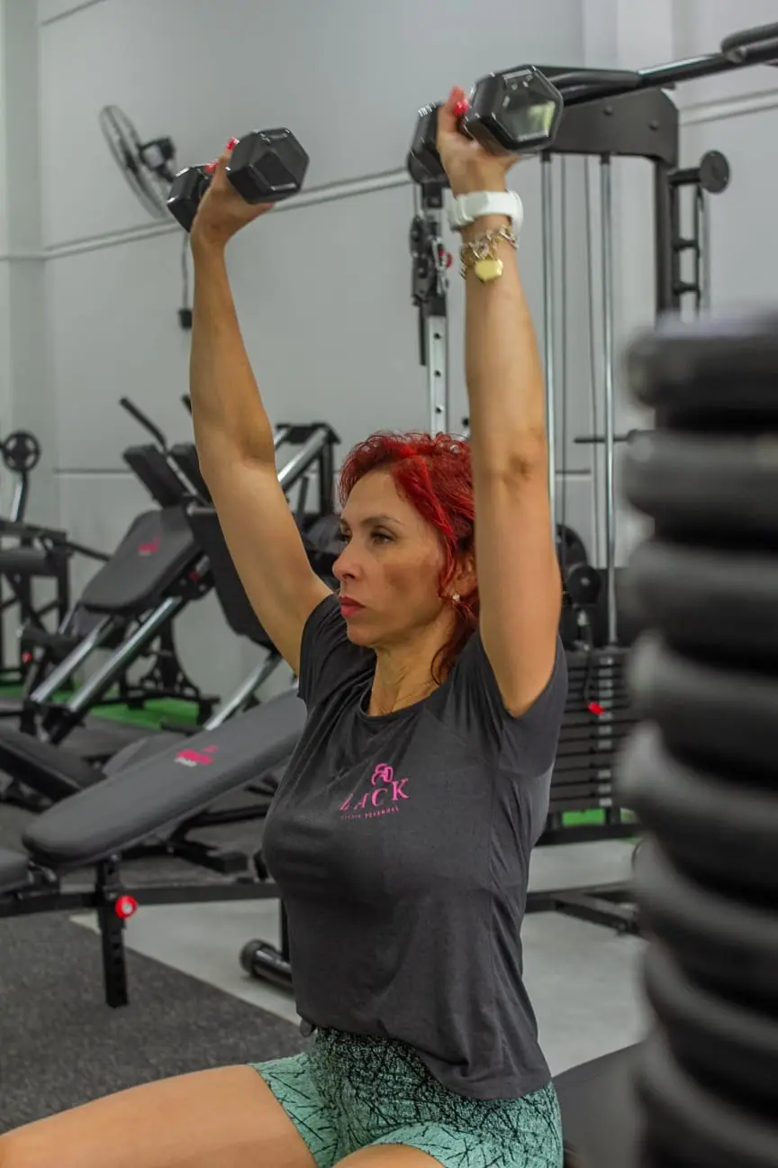 Ereni, personal trainer do Zack Studio, fazendo desenvolvimento com halteres
